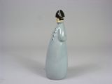 porcelain figurine of a woman with a black hat on her head