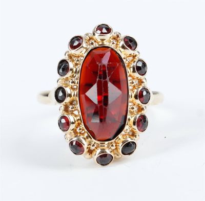 un gros plan d'une bague ornée d'une pierre rouge entourée de grenats