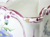 a white vase with purple and blue flowers on it