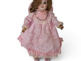 une poupée à l'ancienne, avec une robe rose et des chaussures roses