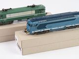 deux petits trains posés sur des cartons, sur une surface blanche