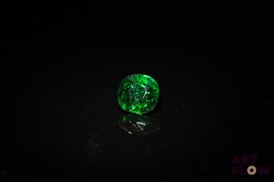 a close up of a green glass ball on a black surface