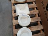 several plates and bowls are stacked on a pallet in a warehouse
