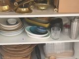 une étagère blanche sur laquelle sont posés tout un tas de plats et d'ustensiles