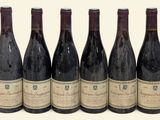 six bouteilles de vin sont alignées sur une surface blanche
