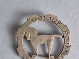 a silver pin with a horse on it on a white surface