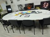 une table blanche avec des chaises noires et des tableaux accrochés au mur