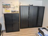 une armoire noire dans un coin de la pièce, à côté d'un bureau