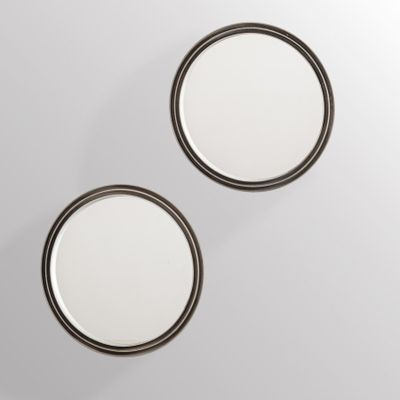 two round mirrors on a wall with a white background