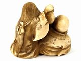 two figurines of a woman and a man sitting on top of each other