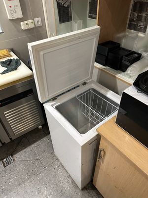 a small refrigerator in a small kitchen with a microwave on top of it