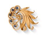un gros plan sur une broche en or sertie de pierres bleues