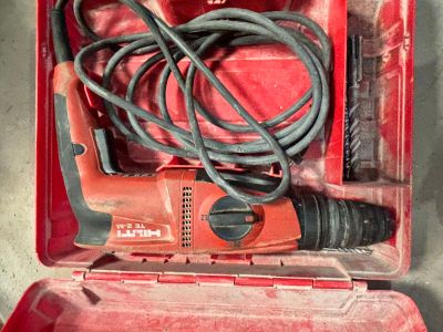 une boîte à outils rouge contenant une perceuse filaire