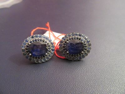 pair of blue and silver earrings on a black surface with a red string