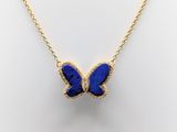 a gold necklace with a blue butterfly pendant on it