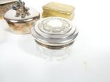 three small glass containers with silver lids on a white surface