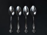 four spoons are lined up in a row on a black surface
