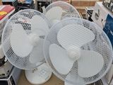 plusieurs ventilateurs blancs posés sur une boîte en carton sous une tente