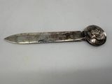 an old silver knife with a coin on it sitting on top of a table