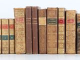 many old books stacked on top of each other on a shelf