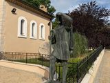 a statue of a man with a hat and a cane in front of a building