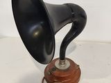 an old black gramphone on a wooden stand on a white surface