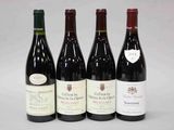 quatre bouteilles de vin sont alignées sur une surface blanche