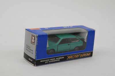 green toy car in a blue box on a white surface