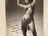 une vieille photo d'une femme en jupe de hula tenant un bout de papier