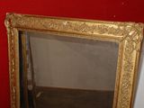 a mirror with a gold frame on a red wall