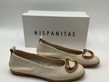 a pair of white shoes with a gold ring on the toe