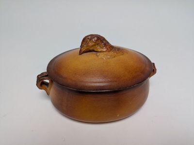 un petit pot marron surmonté d'une feuille