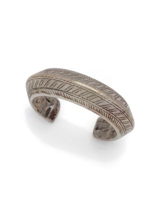 un gros plan d'un bracelet manchette en argent sur fond blanc