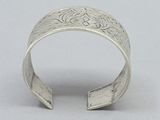 silver cuff bracelet with engraved design on the outside of it