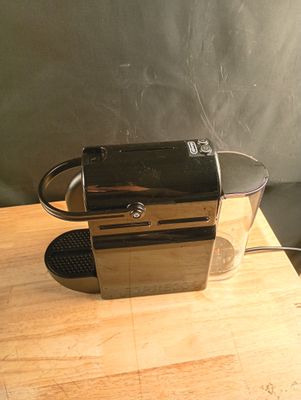 a coffee maker sitting on a table with a cup on it