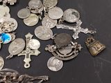 a lot of silver coins and charms on a table