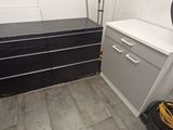 a black and white dresser in a room with a vacuum on the floor