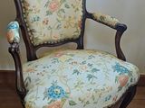 a chair with a floral upholstered seat in front of a window