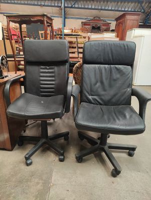 pair of black leather office chairs in a warehouse area