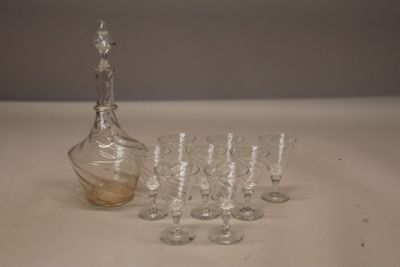 des bouteilles et des verres posés sur une table, avec une carafe en arrière-plan