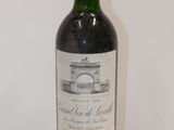 a bottle of red wine sitting on top of a white table