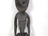 une vieille statue en bois d'un homme avec un chapeau sur la tête