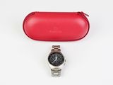 a close up of a watch and a red case on a white surface