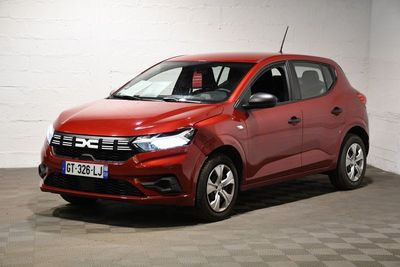 La voiture rouge est garée dans une pièce blanche au sol à carreaux.