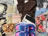 a pile of clothing and a pair of shoes on a bed