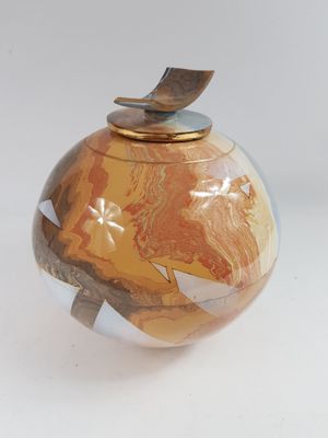 un petit vase avec un couvercle en bois posé sur une surface blanche
