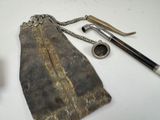 an old purse with a chain and a pipe on a table