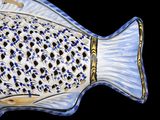 a blue and white fish shaped dish on a black background