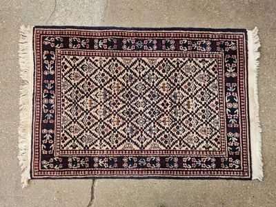 Tapis en laine à motifs de losanges rouges sur fond beige.