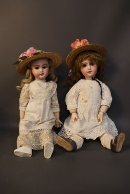 pair of antique porcelain dolls sitting next to each other on a black background